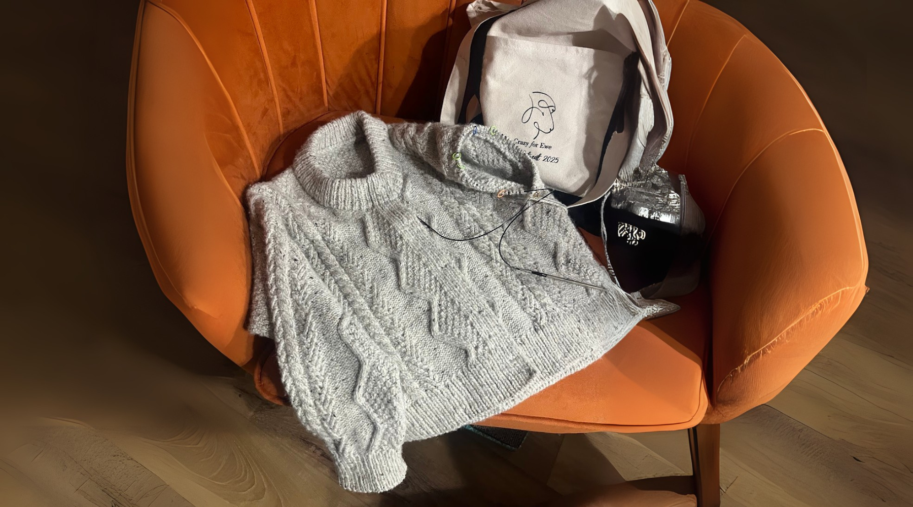 gray cabled cardigan on orange chair with one sleeve complete