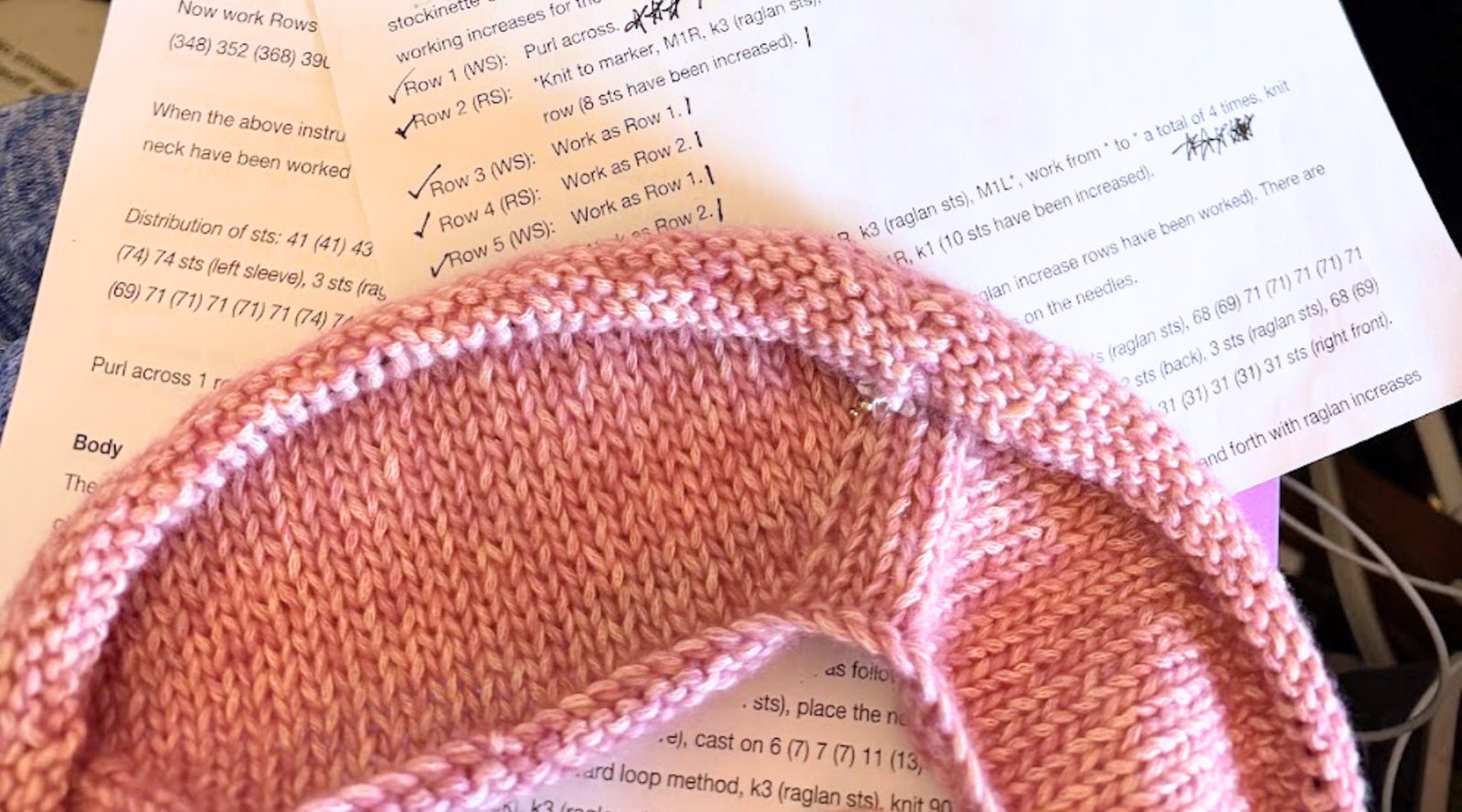 Pink Champagne Cardigan in progress over a marked-up knitting pattern