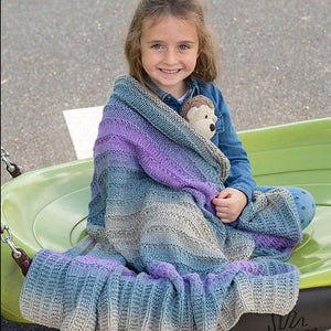 little girl wrapped in blue and purple blanket and holding a stuffed town