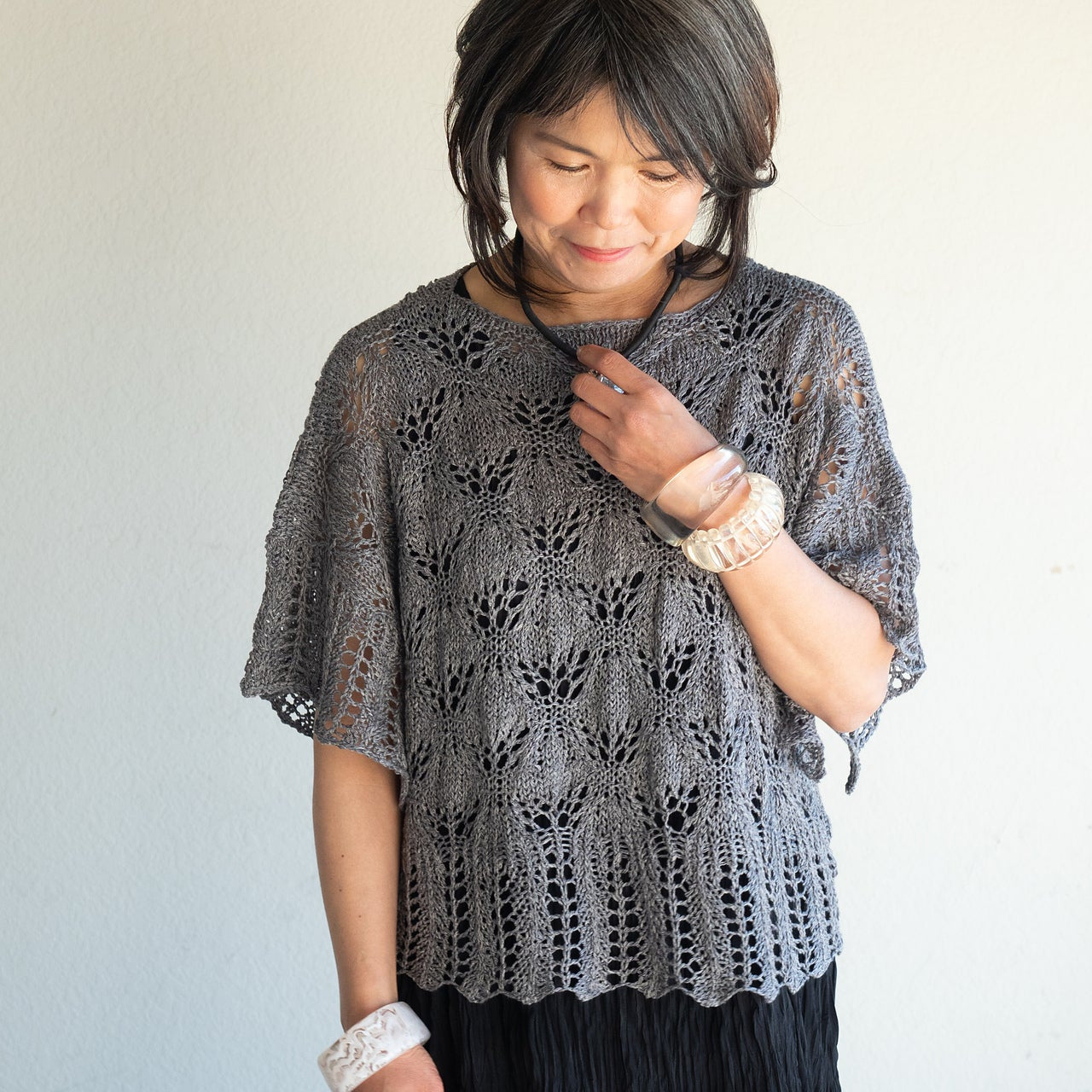 Woman wearing a gray lace top against a plain background