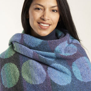 Kaffe fassett Marble wrap kit Woman with dark hair wearing wrap with large polka dots in gradient yarn
